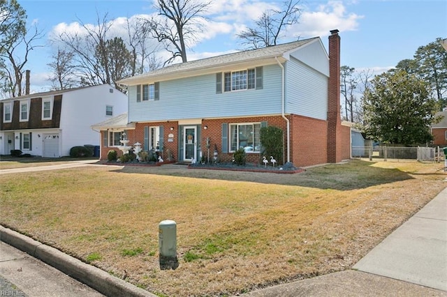 colonial home featuring a front lawn, fence, brick siding, and a chimney