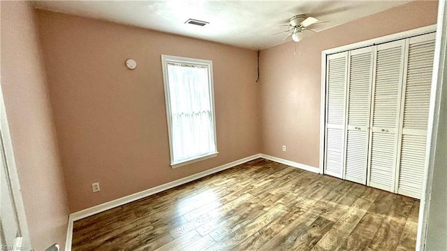 unfurnished bedroom featuring a closet, visible vents, baseboards, and wood finished floors