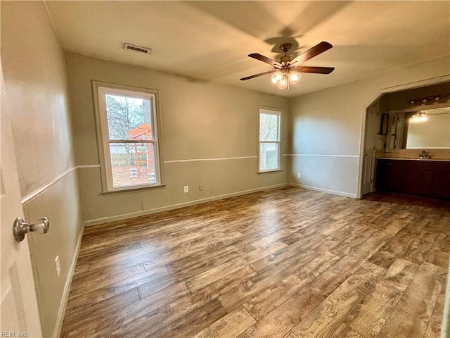 unfurnished bedroom with a sink, wood finished floors, visible vents, and baseboards