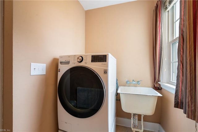 laundry area with laundry area, washer / dryer, a healthy amount of sunlight, and a sink