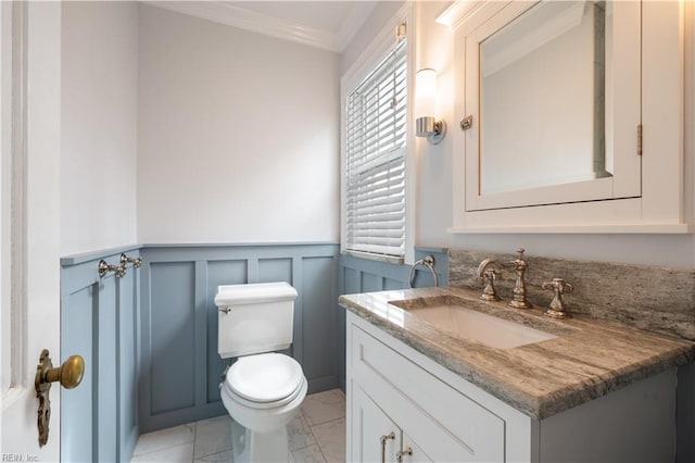 bathroom with vanity, wainscoting, crown molding, toilet, and marble finish floor