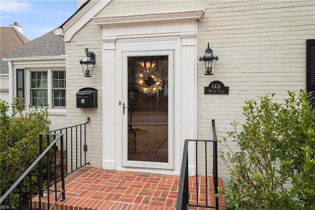 entrance to property with brick siding and roof with shingles