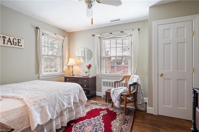 bedroom featuring radiator, multiple windows, wood finished floors, and baseboards