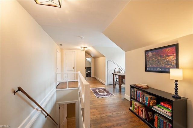 hall featuring wood finished floors, an upstairs landing, and baseboards