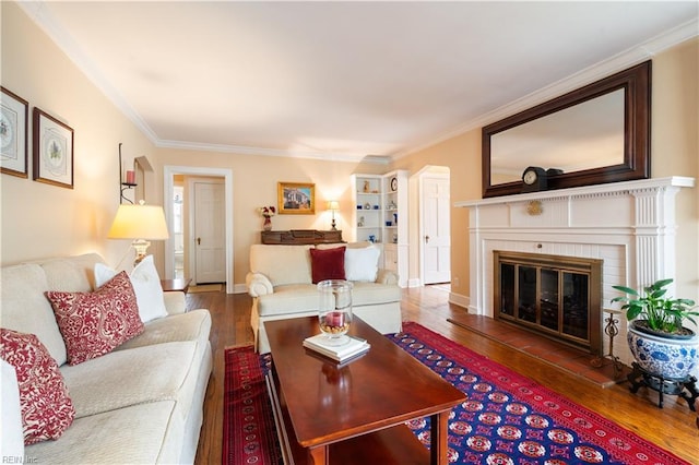 living area featuring a brick fireplace, crown molding, baseboards, and wood finished floors