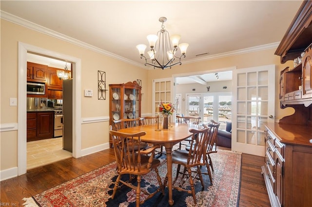 dining room featuring wood finished floors, baseboards, ornamental molding, french doors, and a notable chandelier