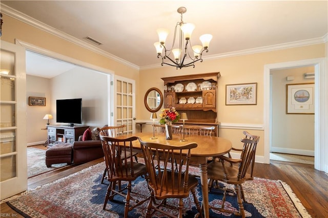 dining space with visible vents, ornamental molding, wood finished floors, an inviting chandelier, and baseboards