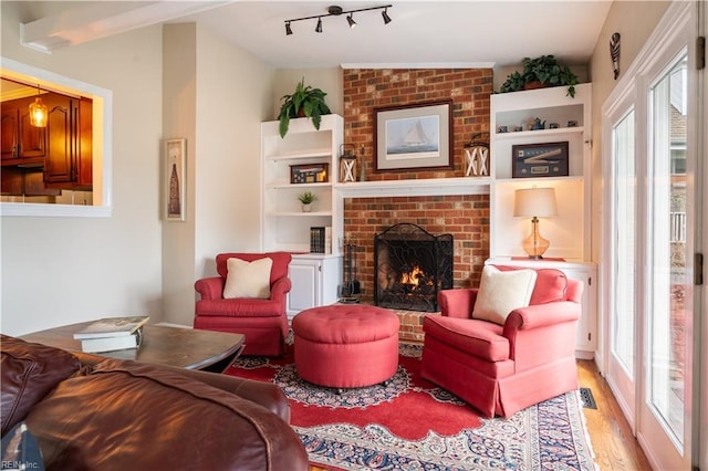 living room with track lighting, a fireplace, and light wood finished floors