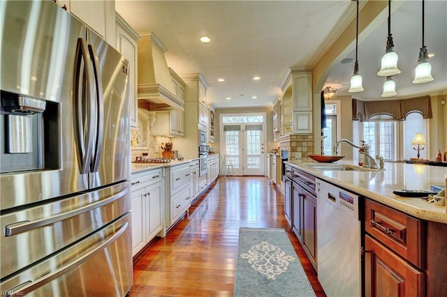 kitchen featuring a healthy amount of sunlight, premium range hood, appliances with stainless steel finishes, and a sink