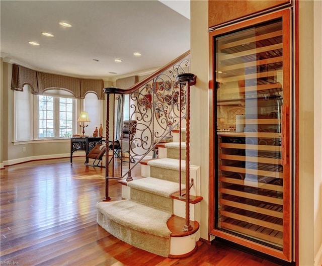 stairs with recessed lighting, baseboards, wine cooler, and wood finished floors