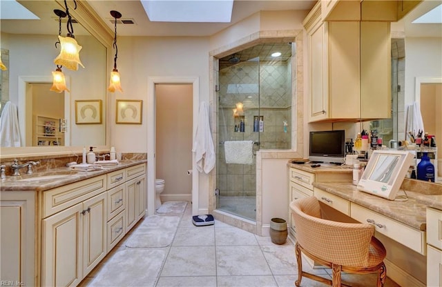 bathroom featuring toilet, double vanity, a stall shower, a skylight, and a sink