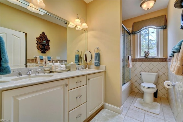 bathroom featuring double vanity, a sink, tile patterned flooring, tile walls, and toilet