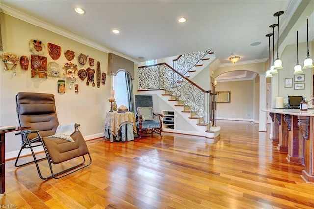 living area with light wood-type flooring, ornamental molding, stairway, arched walkways, and ornate columns