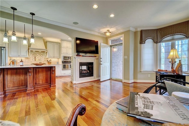 living room featuring baseboards, recessed lighting, a multi sided fireplace, light wood-style floors, and crown molding