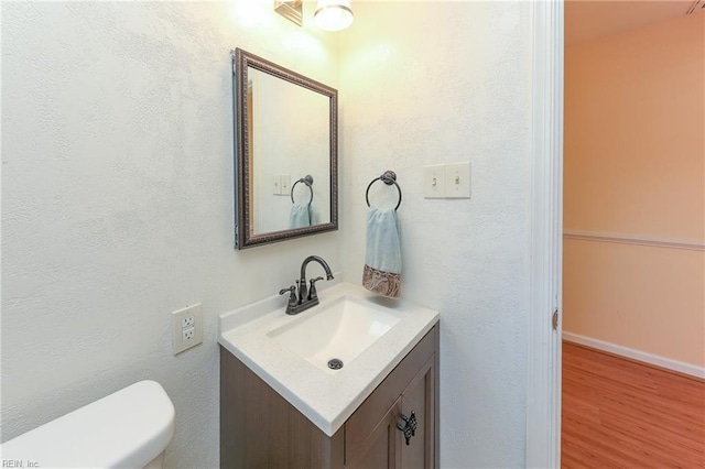 bathroom featuring toilet, wood finished floors, and vanity