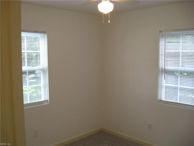 carpeted spare room featuring baseboards and a ceiling fan