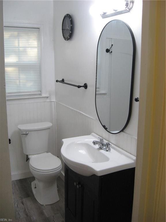 bathroom featuring a wainscoted wall, toilet, vanity, and wood finished floors