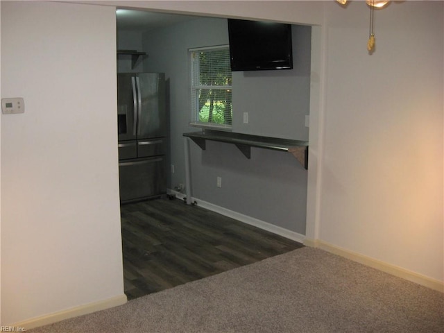 kitchen with black fridge, dark carpet, and baseboards