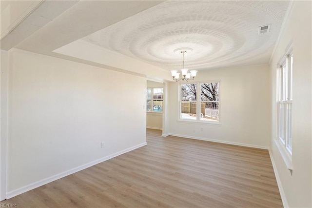 unfurnished dining area featuring a tray ceiling, visible vents, light wood-style flooring, and an inviting chandelier