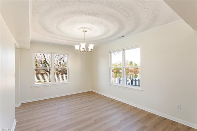 spare room featuring baseboards, light wood-type flooring, and a chandelier