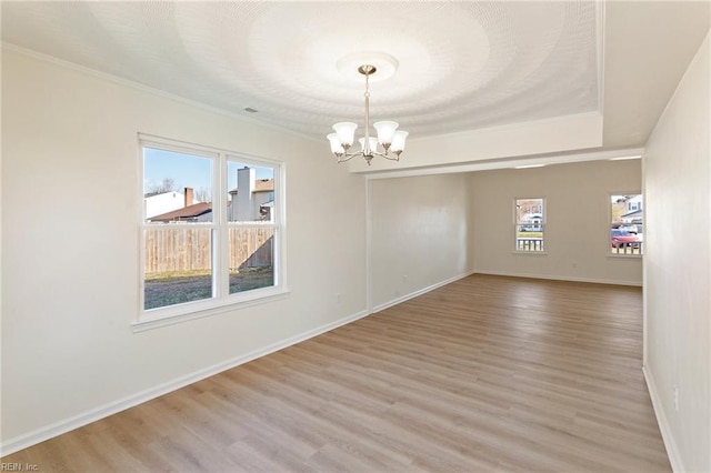 spare room with baseboards, a notable chandelier, crown molding, and light wood finished floors