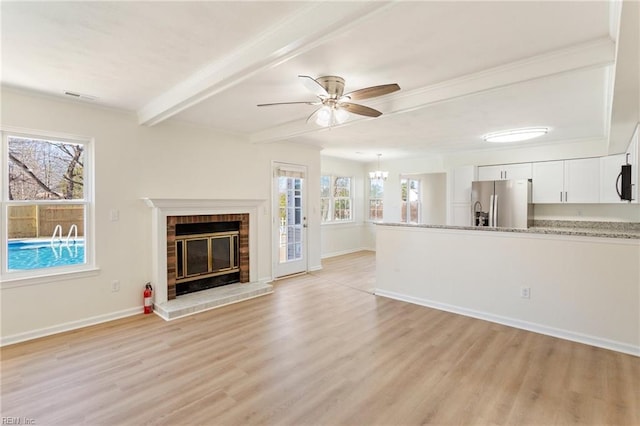 unfurnished living room with beam ceiling, plenty of natural light, a fireplace, and visible vents