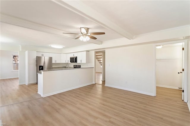 kitchen featuring beamed ceiling, light wood-style flooring, appliances with stainless steel finishes, white cabinets, and a sink