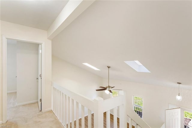 corridor featuring an upstairs landing, baseboards, light carpet, and a skylight