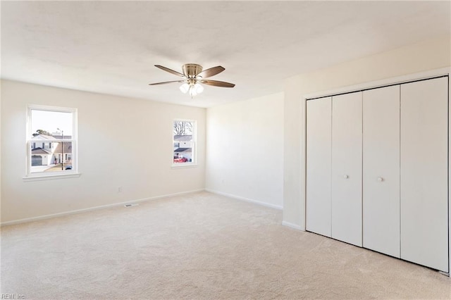 unfurnished bedroom with carpet flooring, multiple windows, baseboards, and a closet