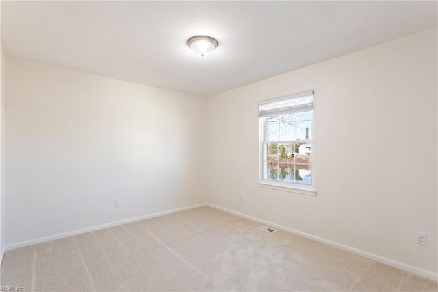 unfurnished room featuring visible vents, light colored carpet, and baseboards