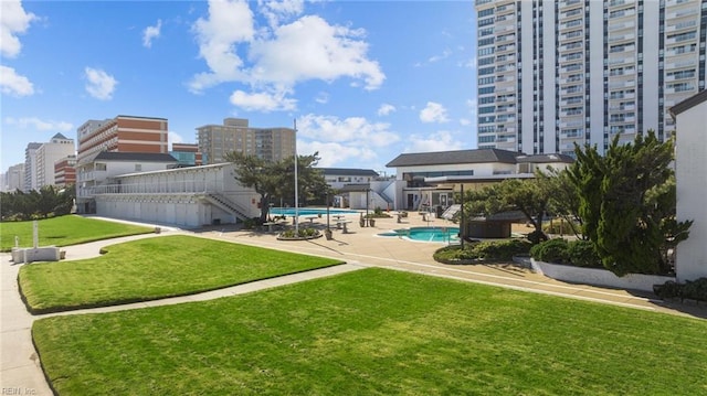 exterior space featuring a city view, a yard, a swimming pool, and a patio area