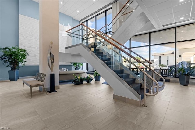 staircase with a high ceiling, recessed lighting, a drop ceiling, floor to ceiling windows, and tile patterned floors