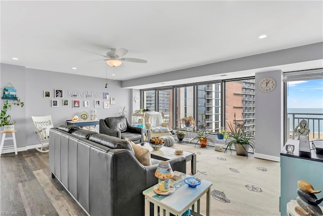 living area featuring recessed lighting, a ceiling fan, baseboards, and wood finished floors