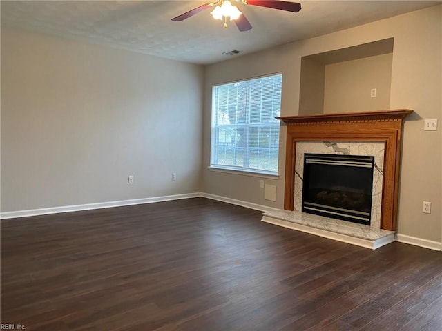 unfurnished living room with ceiling fan, dark wood-type flooring, baseboards, and a premium fireplace