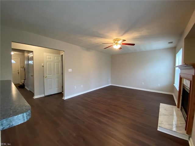 unfurnished living room with a ceiling fan, a fireplace with flush hearth, dark wood-style floors, and baseboards