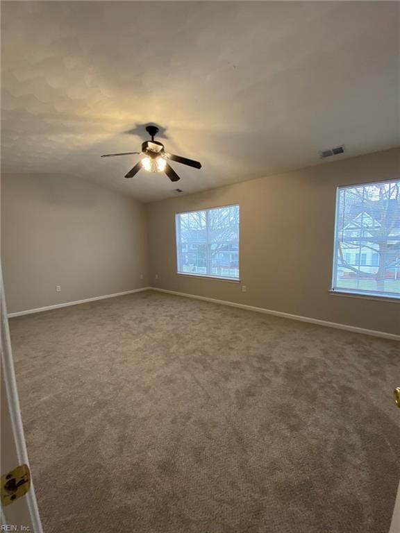 spare room featuring visible vents, dark carpet, baseboards, and vaulted ceiling