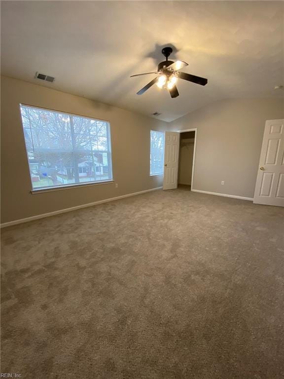 spare room featuring vaulted ceiling, carpet flooring, baseboards, and visible vents