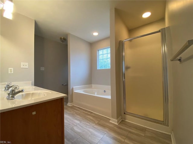 full bath with baseboards, a garden tub, double vanity, a stall shower, and a sink