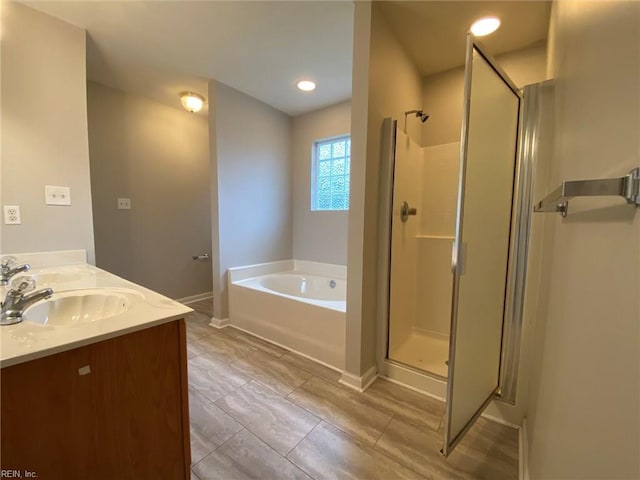 full bath with a bath, a shower stall, baseboards, and a sink