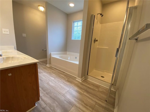 full bathroom featuring baseboards, double vanity, a sink, a shower stall, and a bath