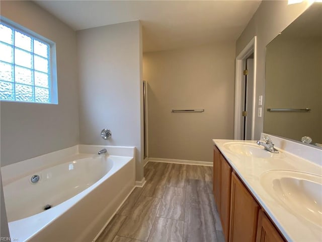 full bath featuring double vanity, a bath, baseboards, and a sink