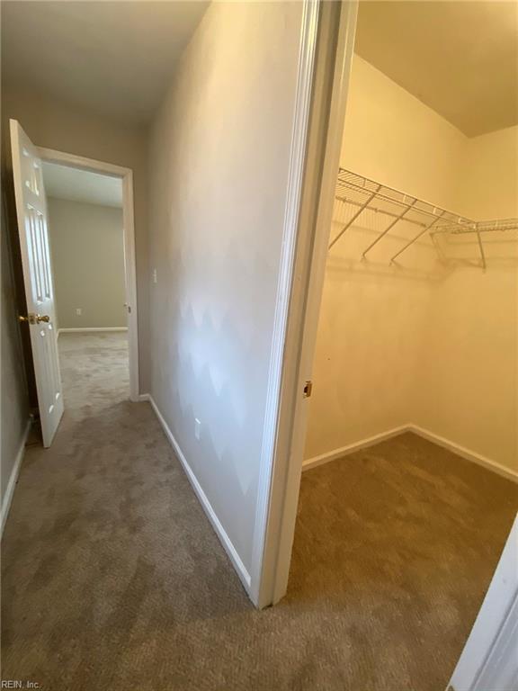 hallway featuring carpet flooring and baseboards