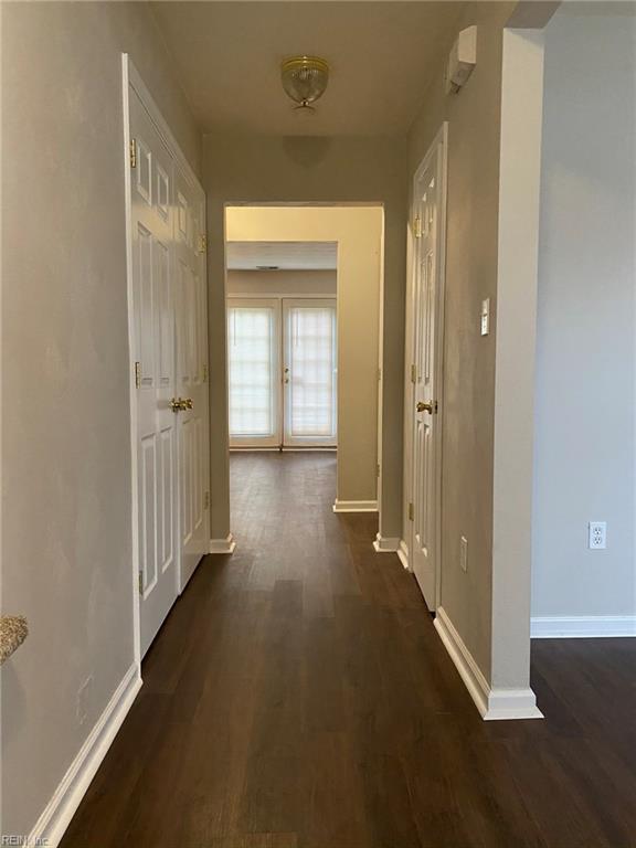 hallway featuring baseboards and dark wood-style flooring