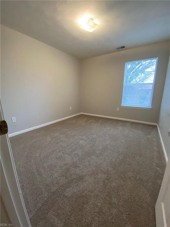 empty room with baseboards and dark carpet