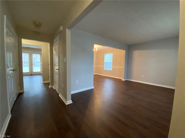 hallway with dark wood finished floors, an inviting chandelier, and baseboards