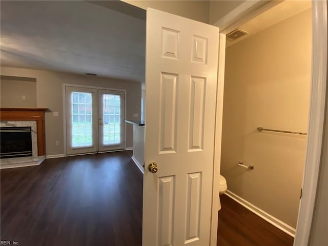 interior space with a high end fireplace, visible vents, baseboards, toilet, and wood finished floors