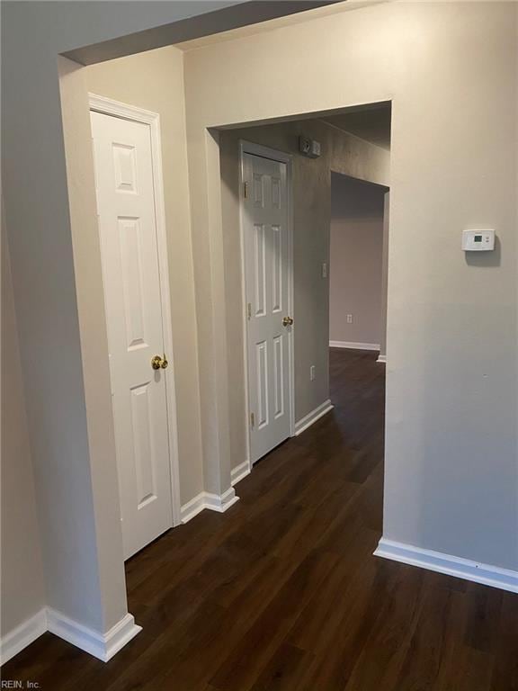 hall with baseboards and dark wood-type flooring