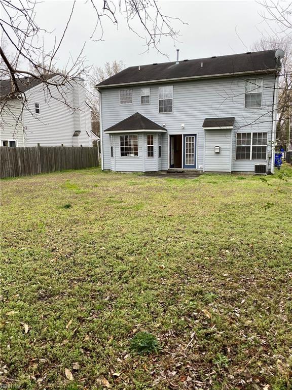 back of property with a lawn, central AC, and fence