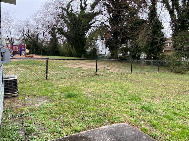 view of yard with central air condition unit, fence, and a playground