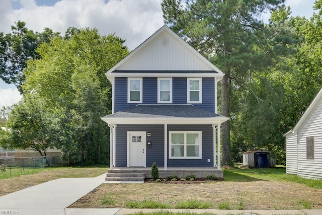 view of front of home featuring a front lawn, fence, a porch, an outdoor structure, and a storage unit